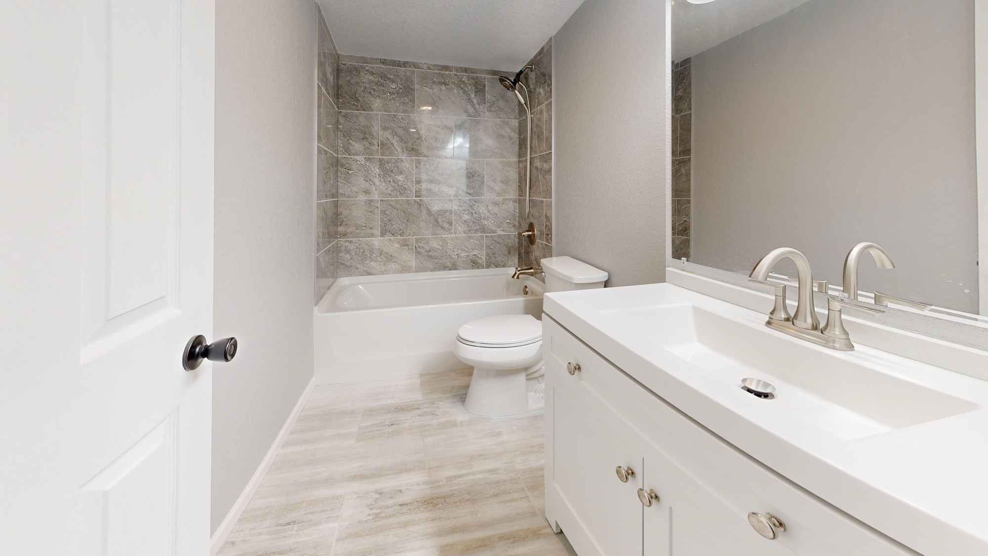 Baño reformado con bañera, alicatado de piedra y mueble blanco