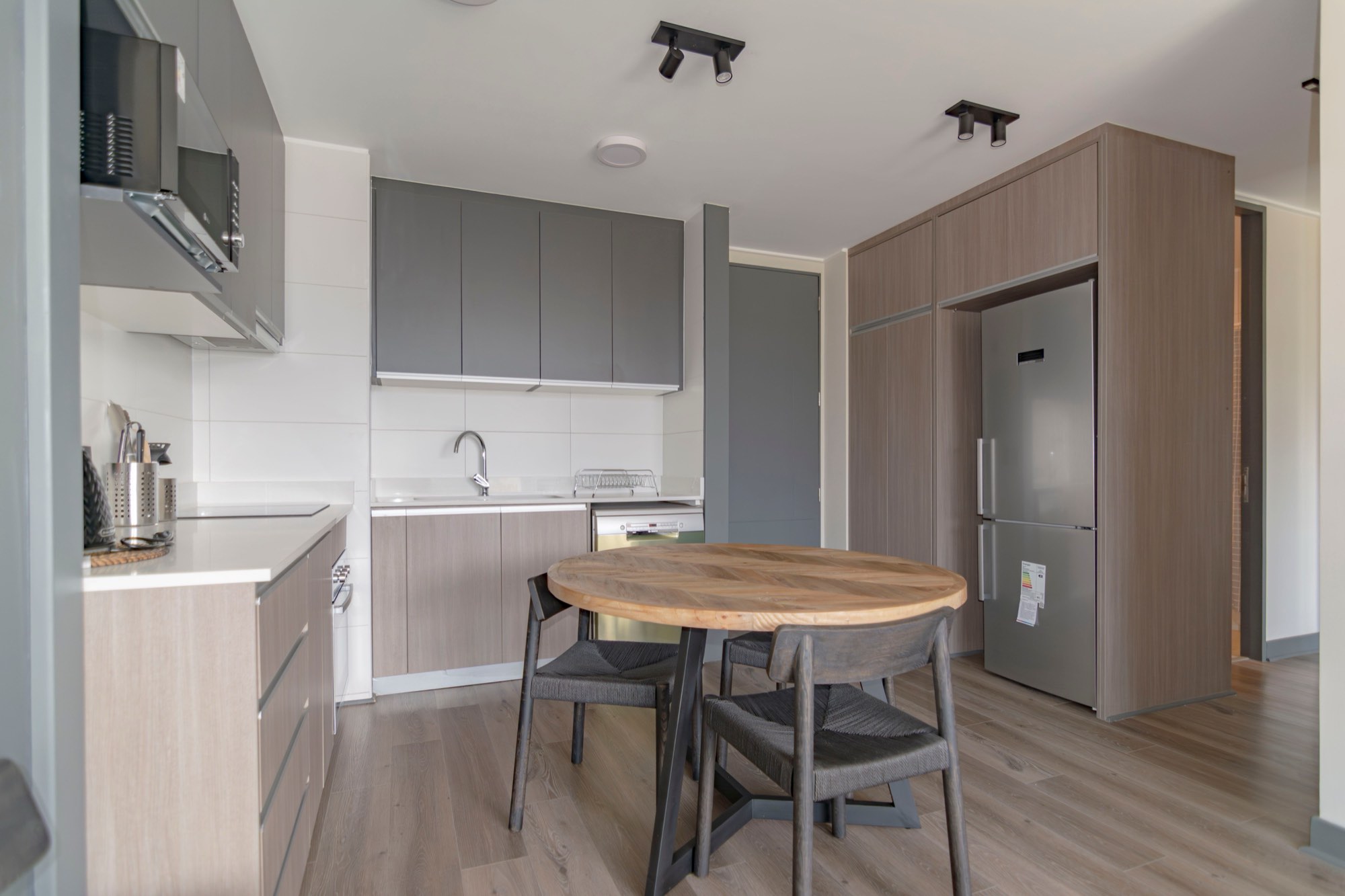 Cocina reformada con muebles grises, madera y mesa redonda